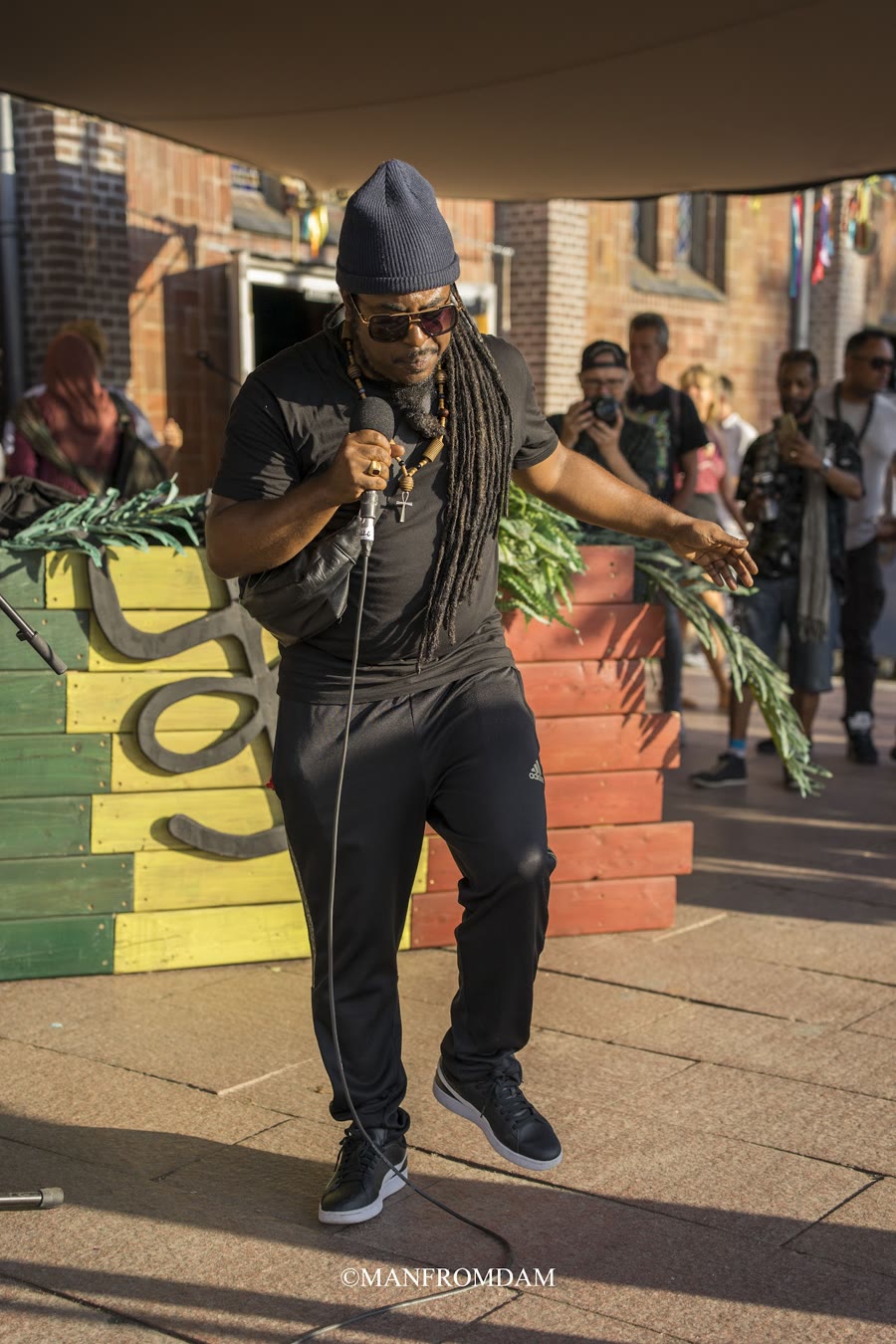 Jah Decko zingt met de band op een buitenpodium