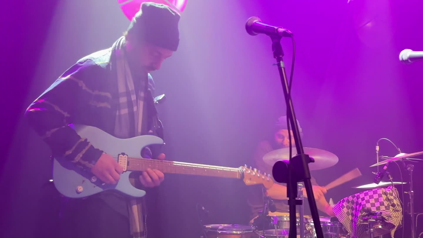 Gitarist en drummer in paars licht
